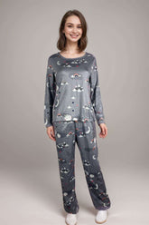 Woman wearing a grey long-sleeve pajama set with cloud and rainbow prints