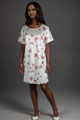 Woman wearing a white satin lounge dress with pink butterfly pattern