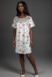 Woman wearing a white satin lounge dress with pink butterfly pattern