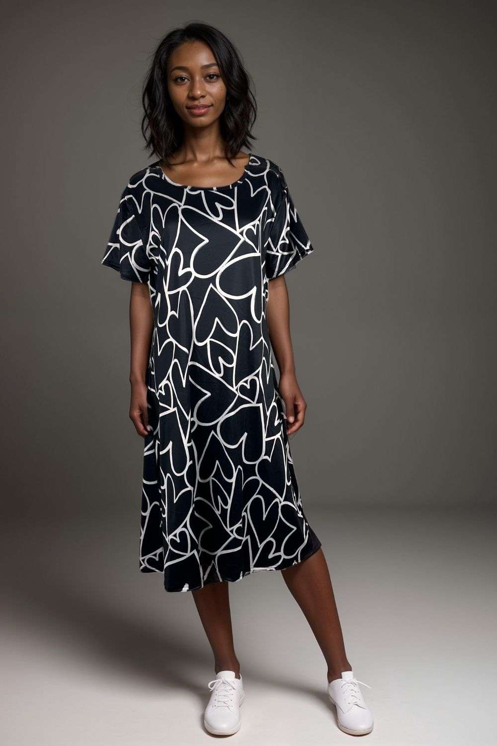 Woman wearing black midi dress with white abstract heart print and flutter sleeves