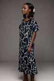 Woman wearing black midi dress with white abstract heart print and flutter sleeves