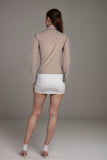 Woman wearing sheer beige mock neck long sleeve top with contrast black stitching