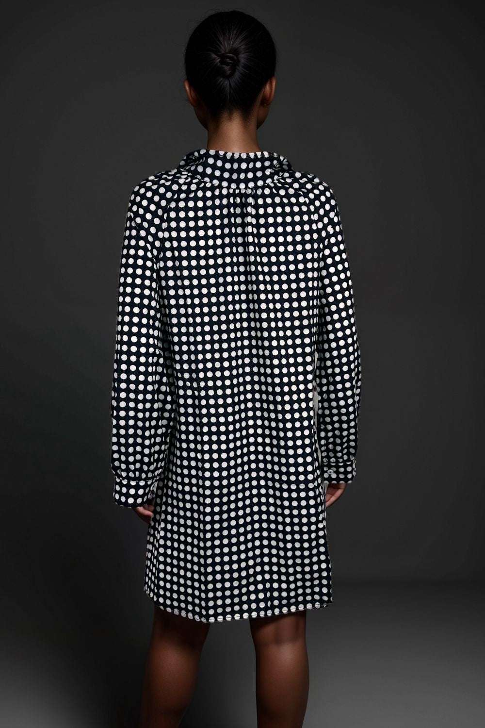 Woman wearing a black and white polka dot long sleeve shirt dress 