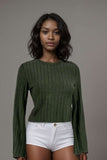 Woman wearing an olive green ribbed knit long sleeve top with white shorts