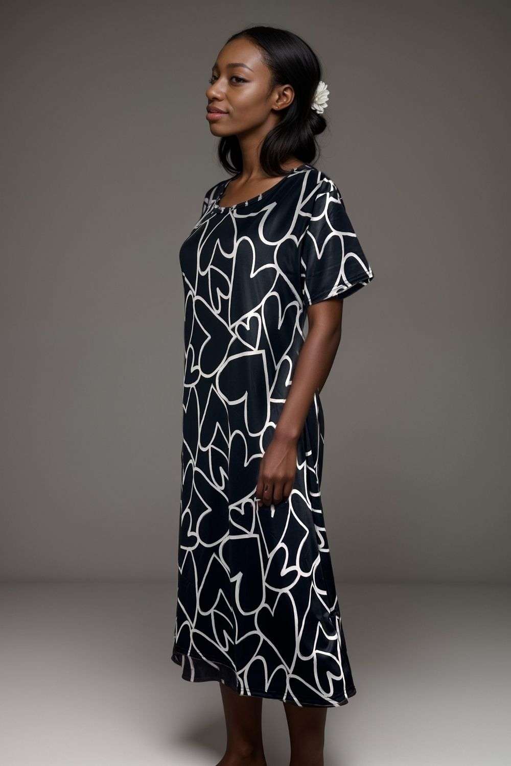 Woman wearing black midi dress with white abstract heart print and flutter sleeves