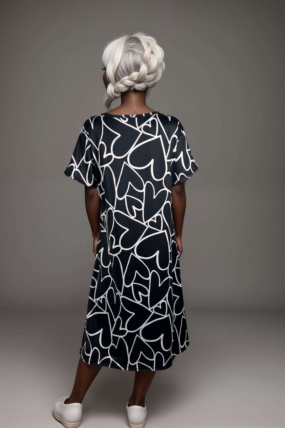 Woman wearing black midi dress with white abstract heart print and flutter sleeves